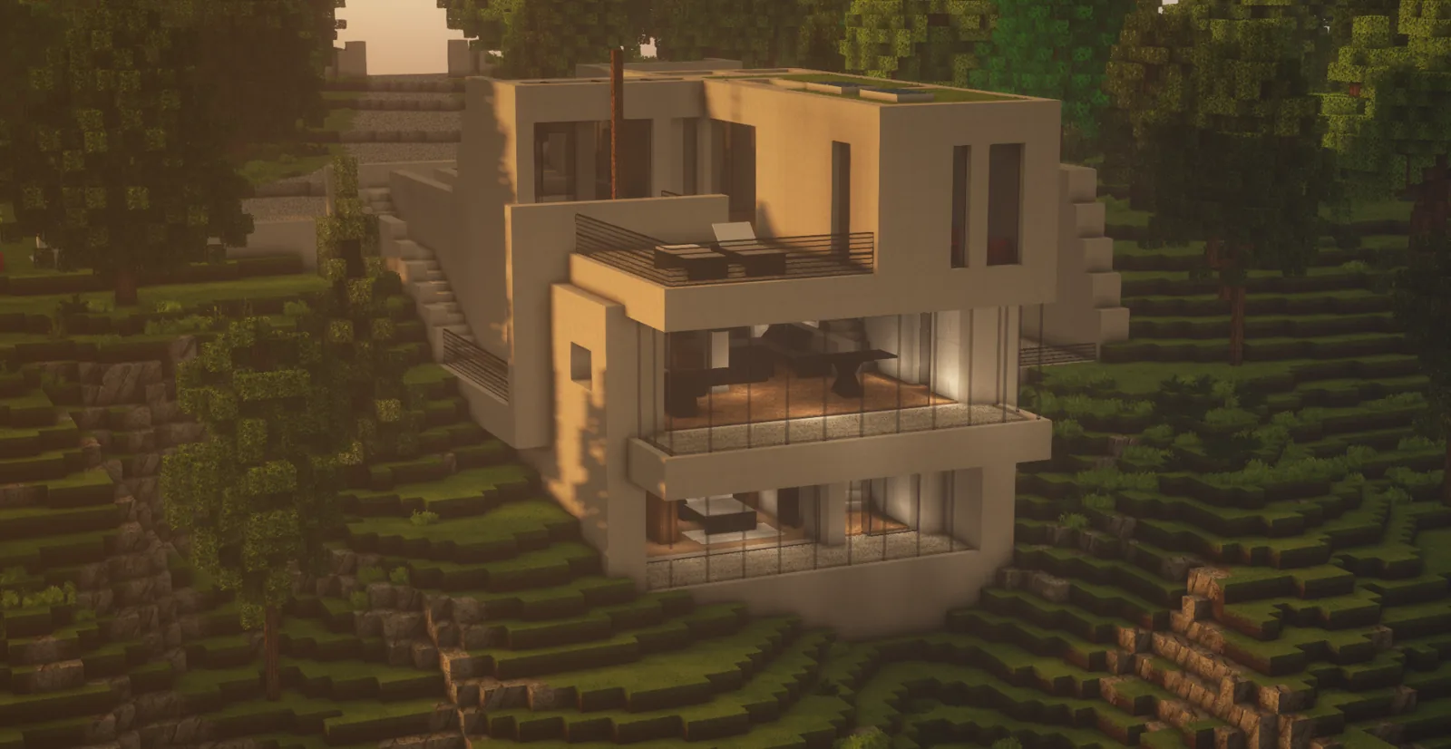 Maison en béton clair à flanc de colline boisée, au crépuscule